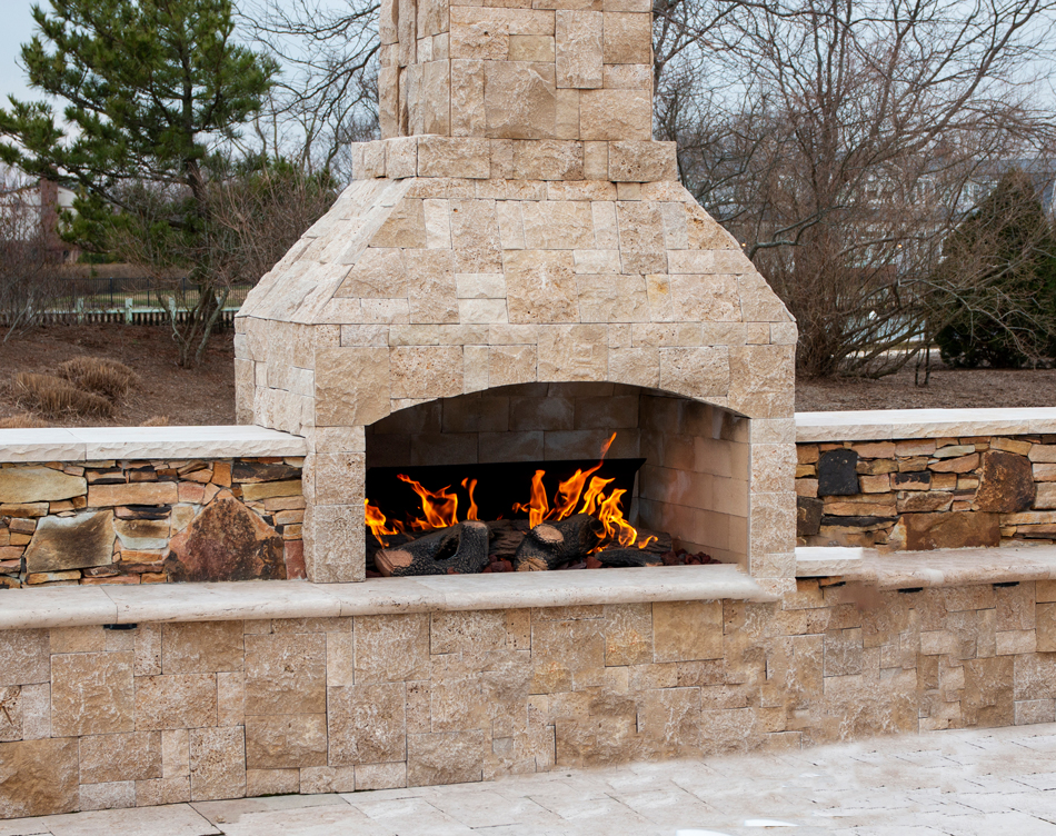 Paving-stone-fireplace-burning-on-deck2-1480965050 A gas fireplace made from paving stone burning outside on a patio close up
